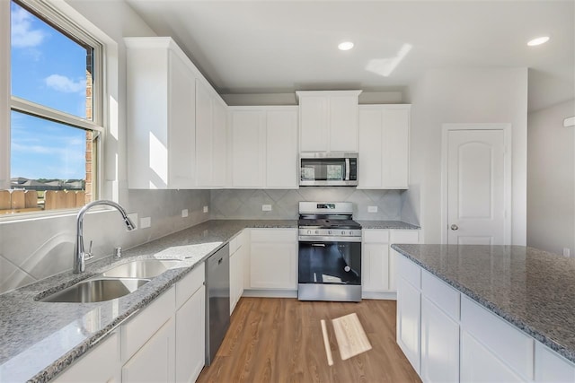 kitchen with sink, stainless steel appliances, light hardwood / wood-style floors, white cabinets, and stone countertops