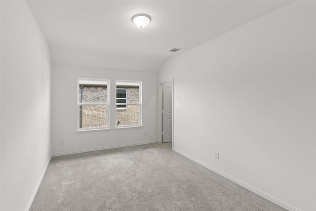 carpeted empty room featuring lofted ceiling