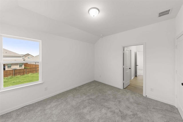 interior space with light carpet and vaulted ceiling