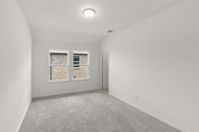 carpeted spare room featuring vaulted ceiling