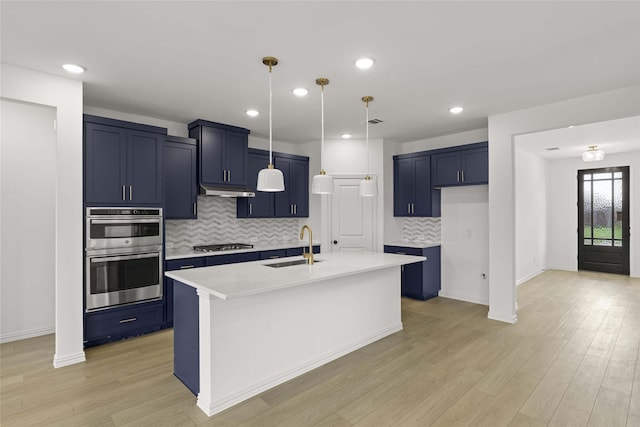 kitchen with an island with sink, appliances with stainless steel finishes, sink, and backsplash