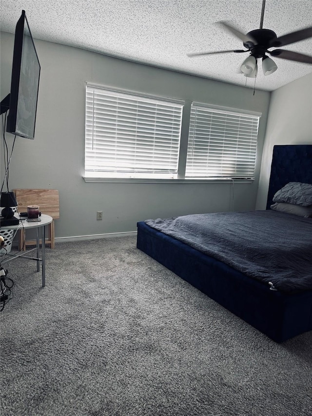 bedroom with ceiling fan, carpet floors, and a textured ceiling