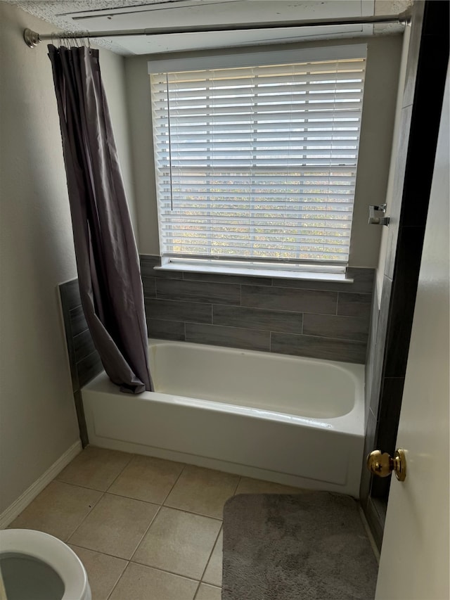 bathroom with shower / bath combination with curtain, tile patterned flooring, toilet, and a wealth of natural light