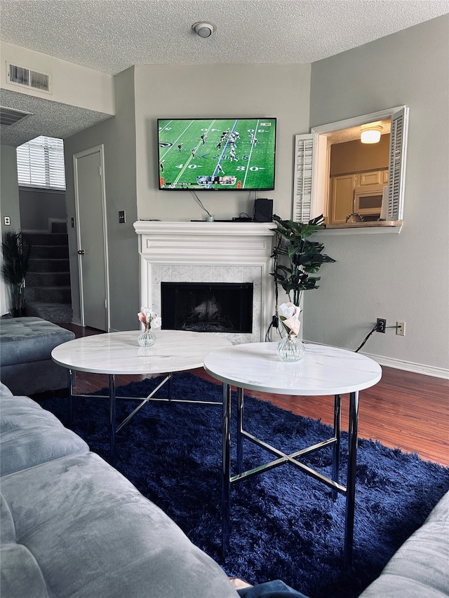 living room featuring a textured ceiling, a tile fireplace, and wood-type flooring