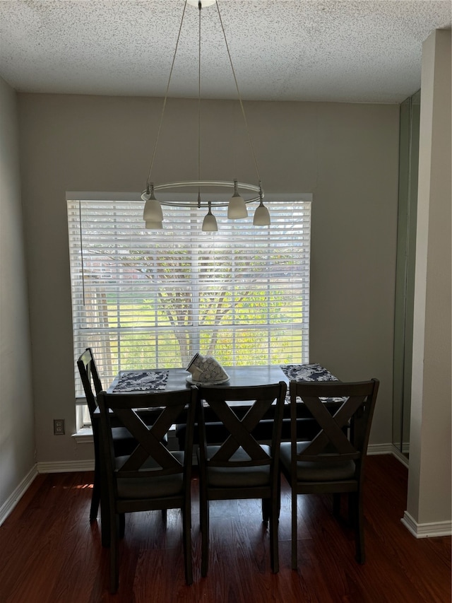 dining room with a textured ceiling and dark hardwood / wood-style flooring