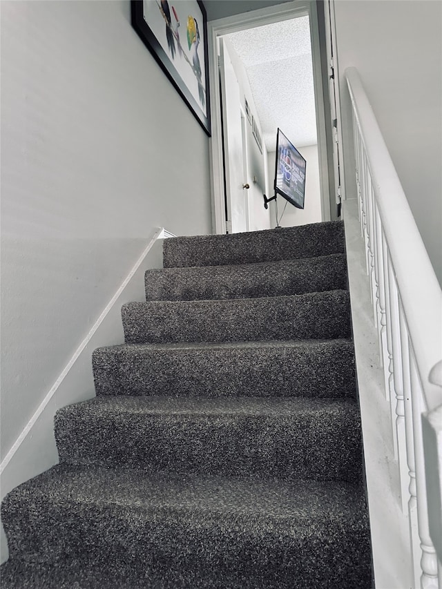 staircase featuring a textured ceiling