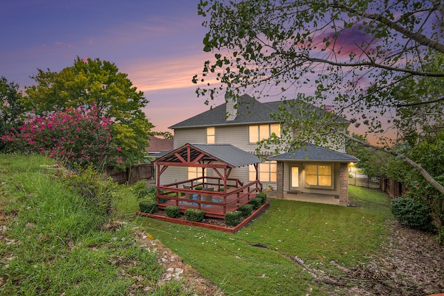 back house at dusk with a lawn, a patio, and a gazebo