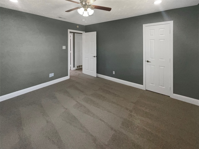 unfurnished room featuring a textured ceiling, dark carpet, and ceiling fan