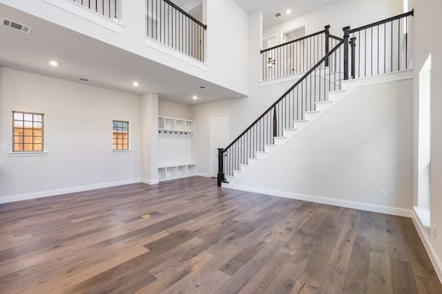 unfurnished living room with wood finished floors, visible vents, and baseboards