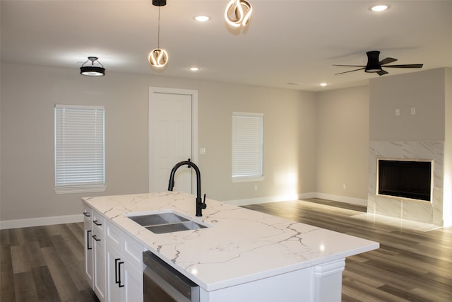 kitchen featuring sink, a kitchen island with sink, decorative light fixtures, dark wood-type flooring, and a fireplace