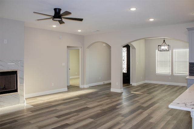 unfurnished living room with ceiling fan with notable chandelier, dark hardwood / wood-style floors, and a high end fireplace