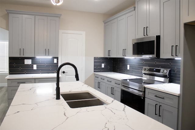 kitchen with gray cabinets, stainless steel appliances, sink, and tasteful backsplash