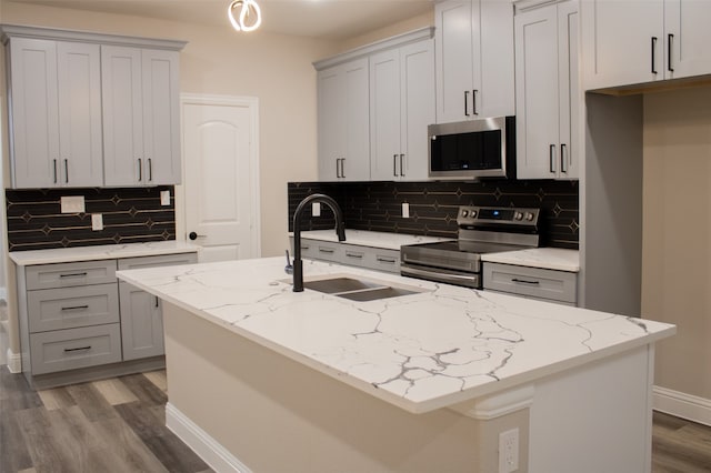 kitchen with light stone countertops, stainless steel appliances, backsplash, and sink