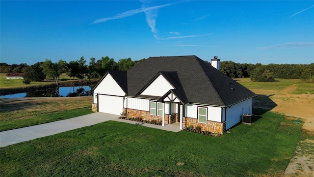 view of front of home featuring a front yard, a garage, a water view, and central AC unit