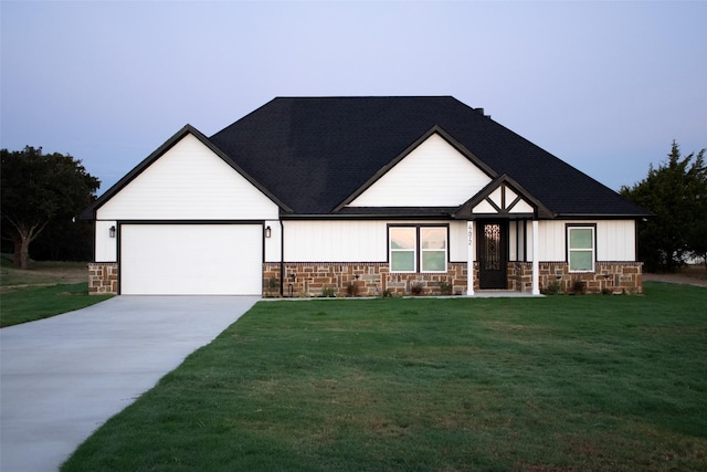 view of front of home featuring stone siding, an attached garage, driveway, and a front lawn