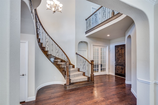 entrance foyer with a notable chandelier, dark hardwood / wood-style flooring, a towering ceiling, and french doors