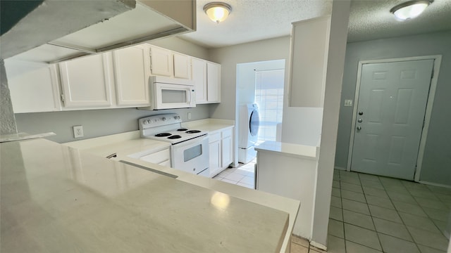 kitchen with a textured ceiling, white appliances, white cabinetry, and light tile patterned floors