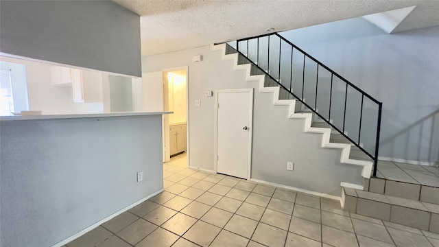 stairway featuring a textured ceiling and tile patterned floors