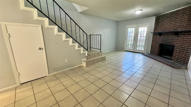 unfurnished living room with a brick fireplace, a textured ceiling, light tile patterned flooring, and french doors