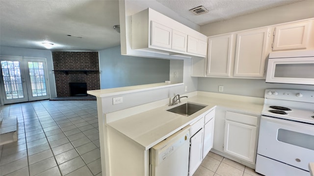 kitchen featuring white cabinetry, a brick fireplace, white appliances, light tile patterned floors, and sink