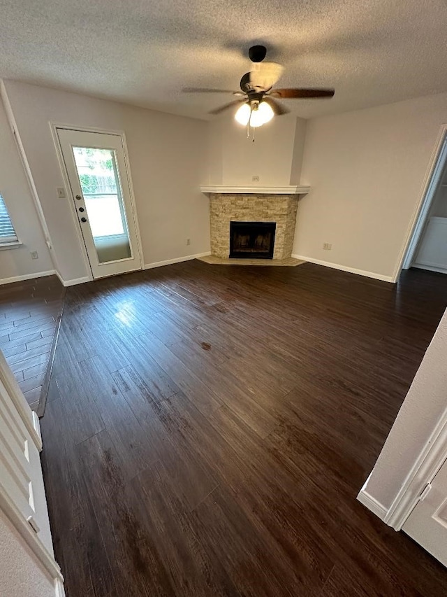 unfurnished living room with dark wood-type flooring, a fireplace, a textured ceiling, and ceiling fan