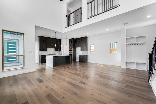 13638 Colony Mews, Frisco, TX 75033 - unfurnished living room featuring a high ceiling, wood finished floors, baseboards, and visible vents