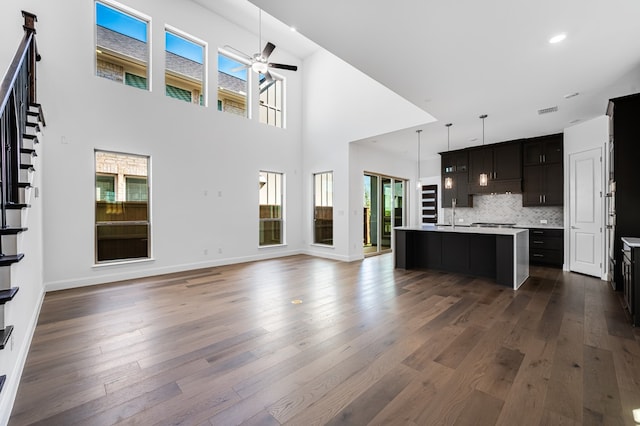 13638 Colony Mews, Frisco, TX 75033 - unfurnished living room featuring visible vents, baseboards, a ceiling fan, dark wood finished floors, and a towering ceiling