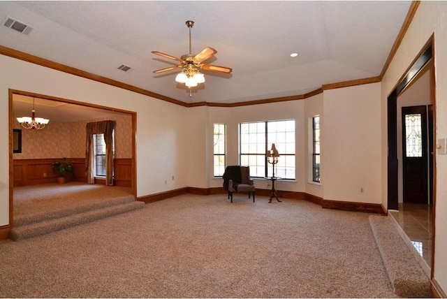 carpeted spare room with ceiling fan with notable chandelier, crown molding, and wood walls