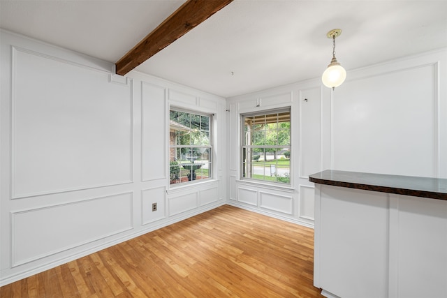 spare room with light wood-type flooring and beamed ceiling