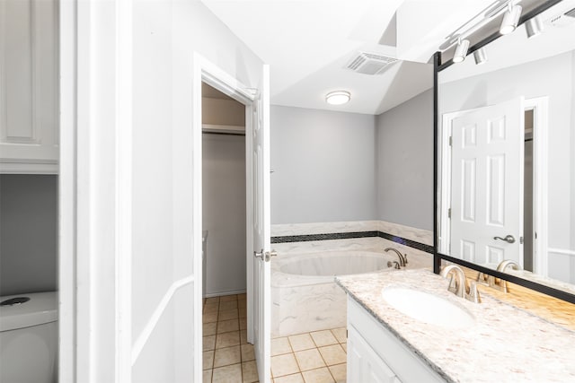 bathroom featuring vanity, a tub to relax in, tile patterned flooring, and toilet