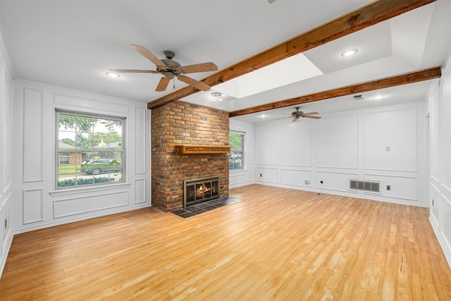 unfurnished living room with ceiling fan, a brick fireplace, and a healthy amount of sunlight