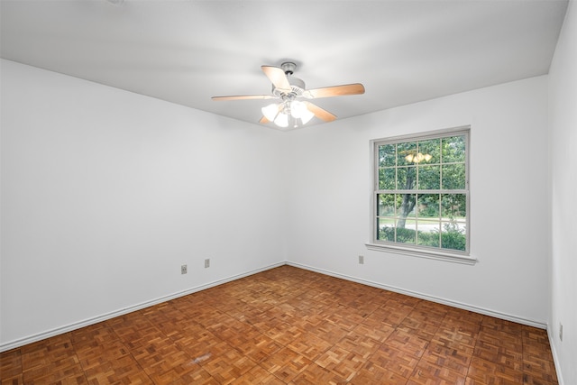 spare room with dark parquet floors and ceiling fan