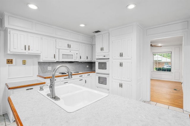 kitchen featuring white cabinets, sink, white appliances, light hardwood / wood-style floors, and decorative backsplash