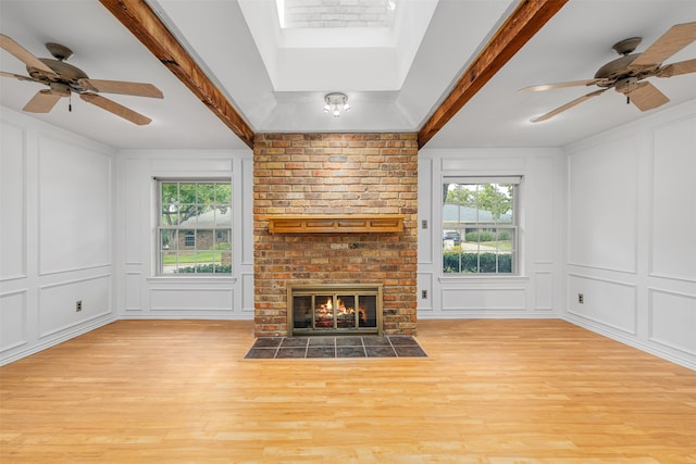 unfurnished living room with a brick fireplace, plenty of natural light, light hardwood / wood-style floors, and ceiling fan