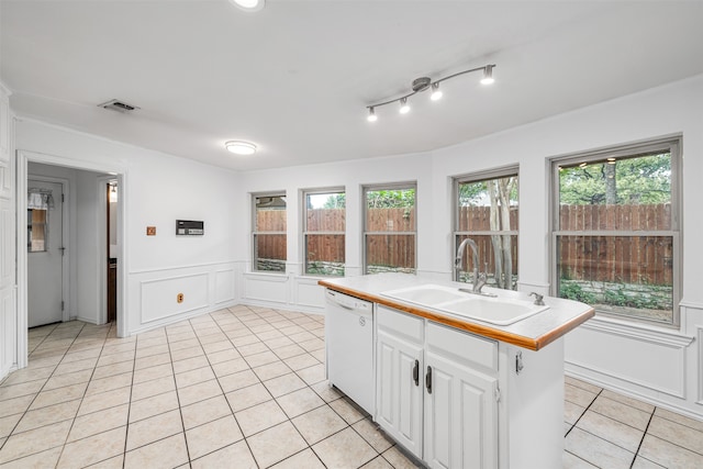 kitchen featuring light tile patterned flooring, an island with sink, white dishwasher, sink, and white cabinetry