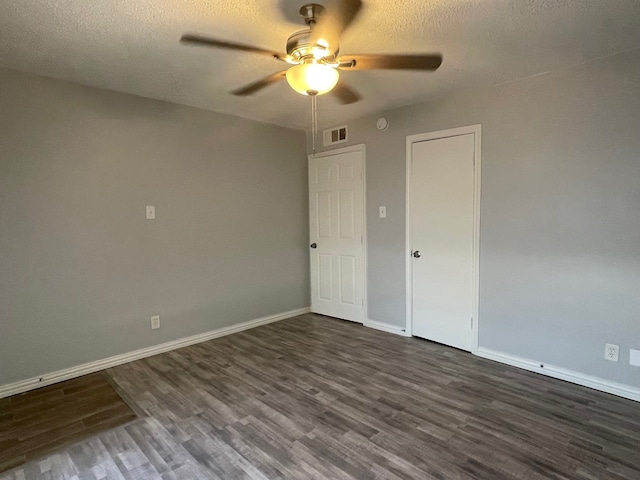 empty room featuring ceiling fan, dark hardwood / wood-style floors, and a textured ceiling