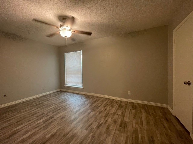 empty room featuring ceiling fan, dark hardwood / wood-style floors, and a textured ceiling