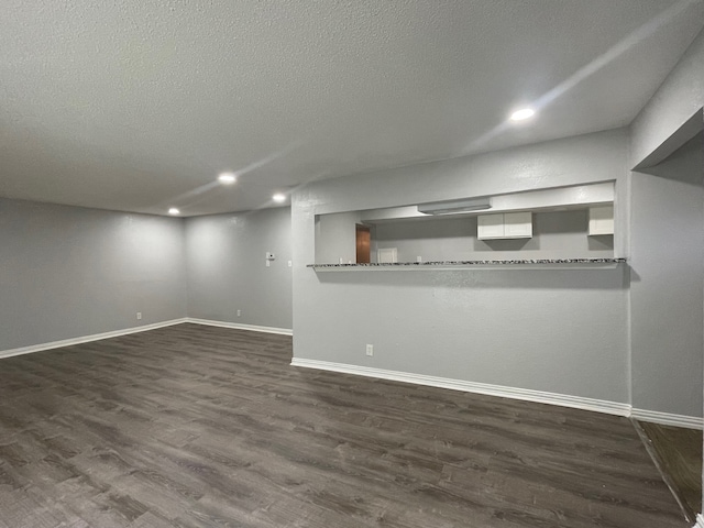 basement with a textured ceiling and dark wood-type flooring