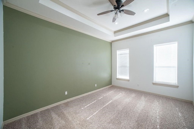 empty room featuring ceiling fan, a raised ceiling, carpet floors, and crown molding