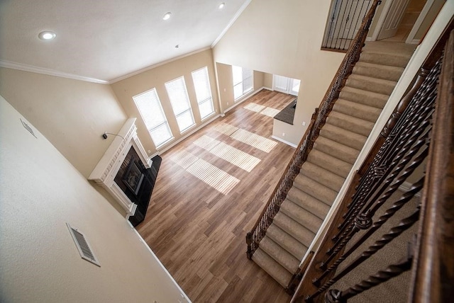 stairway with ornamental molding and hardwood / wood-style floors