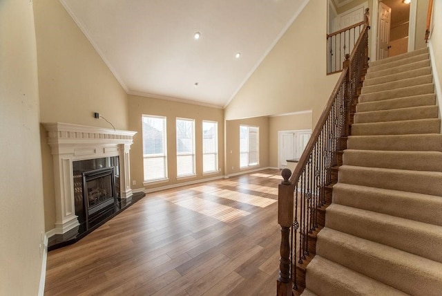 unfurnished living room featuring hardwood / wood-style flooring, a premium fireplace, crown molding, and high vaulted ceiling