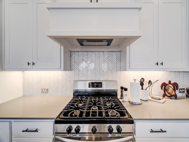 kitchen featuring custom exhaust hood, backsplash, gas range, and white cabinets