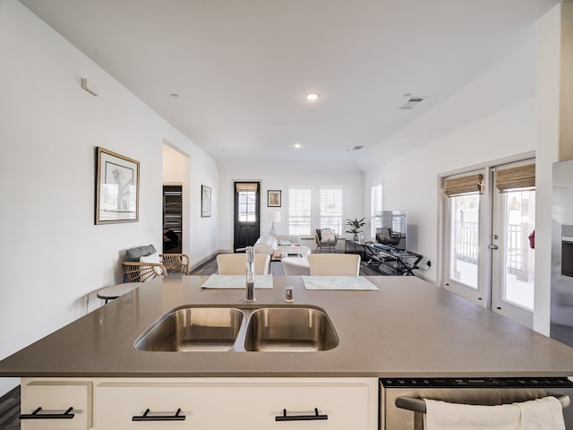 kitchen with a kitchen island with sink, plenty of natural light, stainless steel dishwasher, and white cabinetry