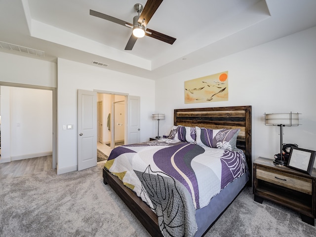 bedroom featuring a raised ceiling, carpet floors, and ceiling fan