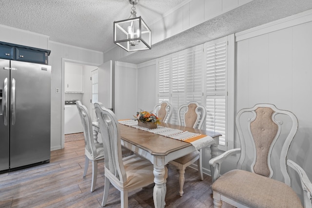 dining room featuring ornamental molding, light hardwood / wood-style floors, a notable chandelier, and a textured ceiling