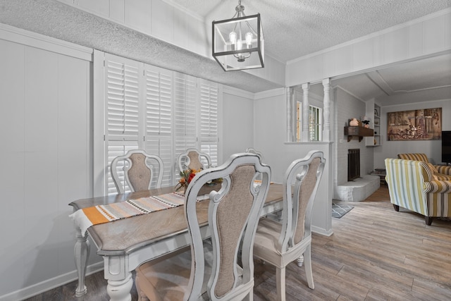 dining room featuring wood-type flooring, a notable chandelier, a textured ceiling, and a wealth of natural light