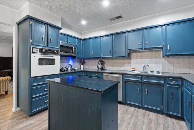 kitchen with appliances with stainless steel finishes, light wood-type flooring, a center island, and blue cabinetry