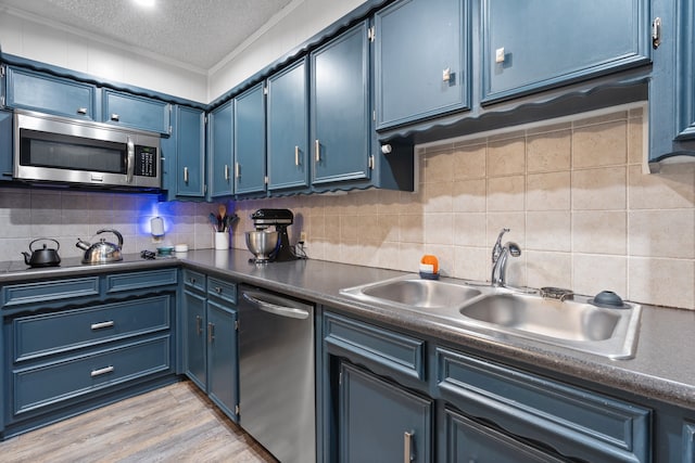 kitchen with appliances with stainless steel finishes, blue cabinets, a textured ceiling, light wood-type flooring, and ornamental molding