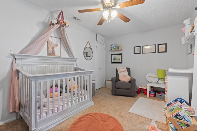 bedroom featuring light colored carpet, ceiling fan, and a nursery area