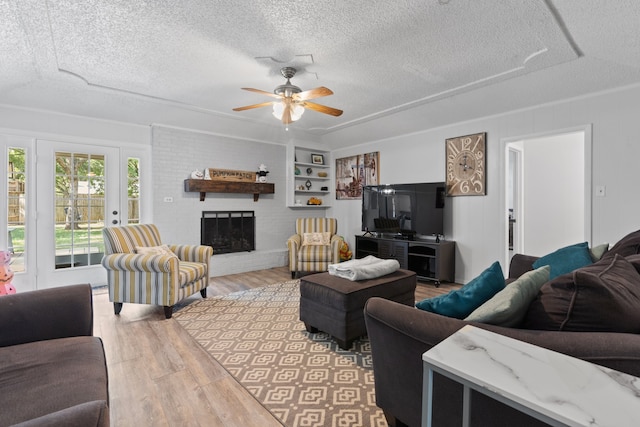 living room with ceiling fan, a textured ceiling, a fireplace, and hardwood / wood-style floors